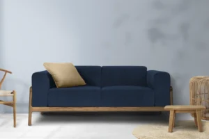 Sofá azul de dos plazas con cojín y estructura de madera en un ambiente interior.
